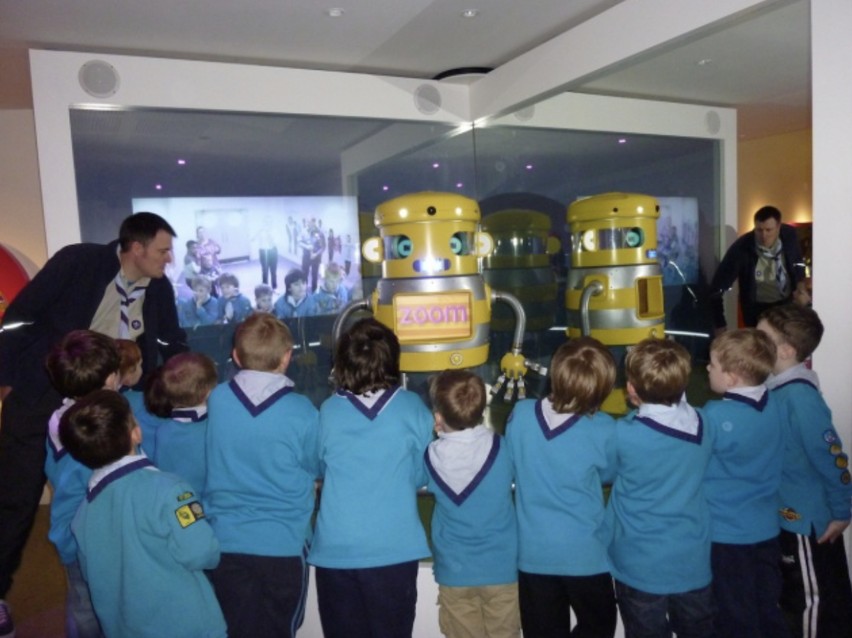 scouts in a group looking at robot